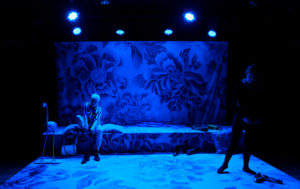 Föreställningsfoto, Ulla Tylén & Tytte Johnsson bredvid varandra med rosa scenografi/bakgrund i blått ljus