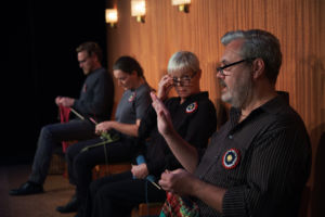 Alla fyra skådespelare i pjäsen sitter på en rad på scenen och stickar