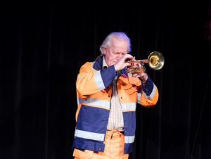 Göran Engman spelar trumpet i arbetskläder med reflexer