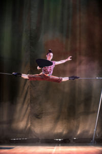 Cirkusartist balanserar på rep i spagat