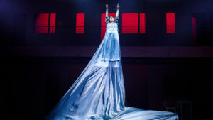 Kvinna med lång klänning flyger i luften på Stora scenen