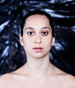 Porträttfoto Sepideh Khodarahmi, mot en bakgrund av svart sopsäck, nakna axlar