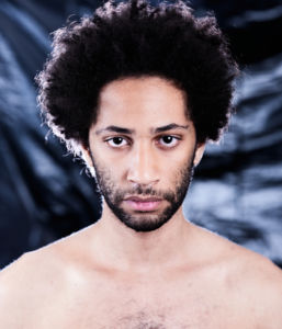 Porträttfoto Lancelot Ncube, mot en bakgrund av svart sopsäck, nakna axlar