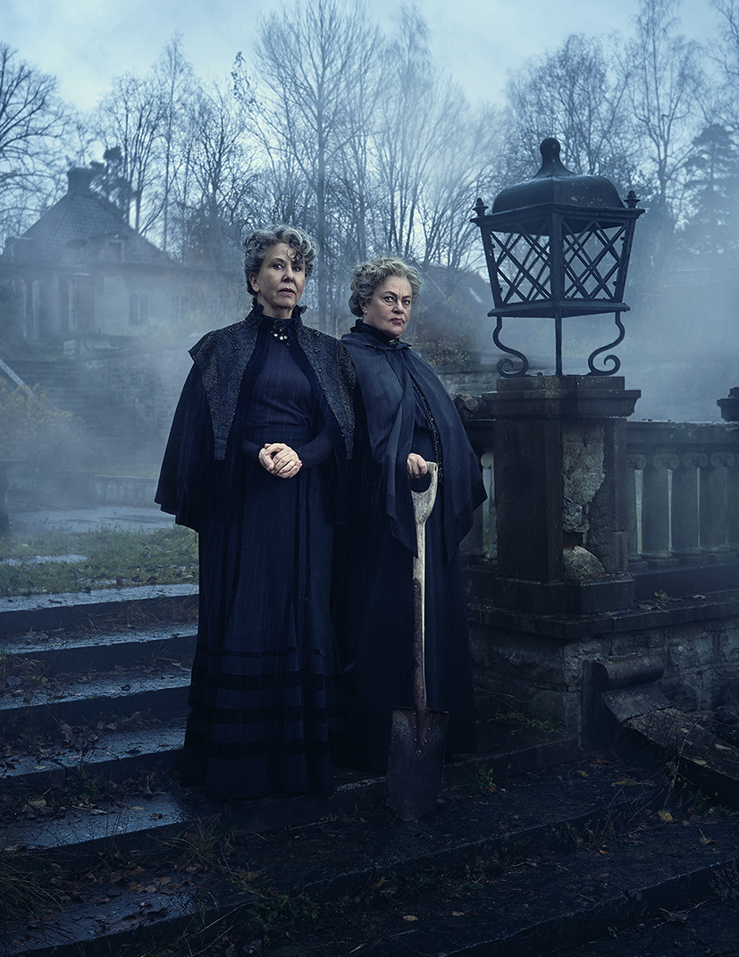 Pia Johansson och Anna Carlson framför ett mörkt och läskigt hus med en spade i handen.