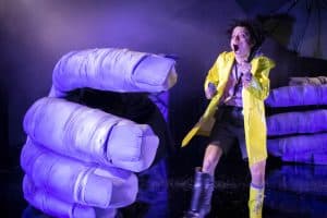 en kvinna i gul regnrock framför en stor hand