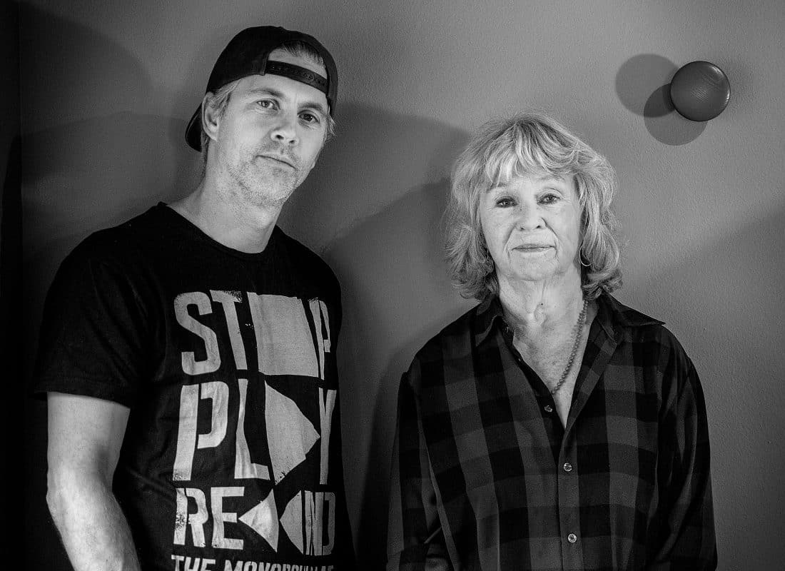 en kvinna och en man står vid en vägg och tuttar in i kameran