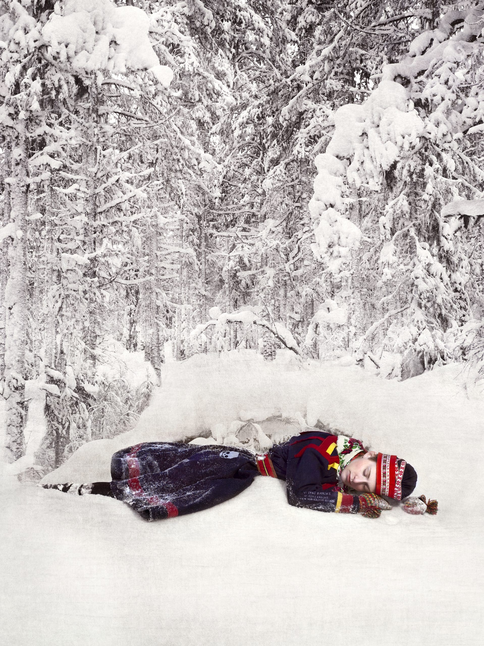 Flicka iklädd kolt ligger ner i snön.