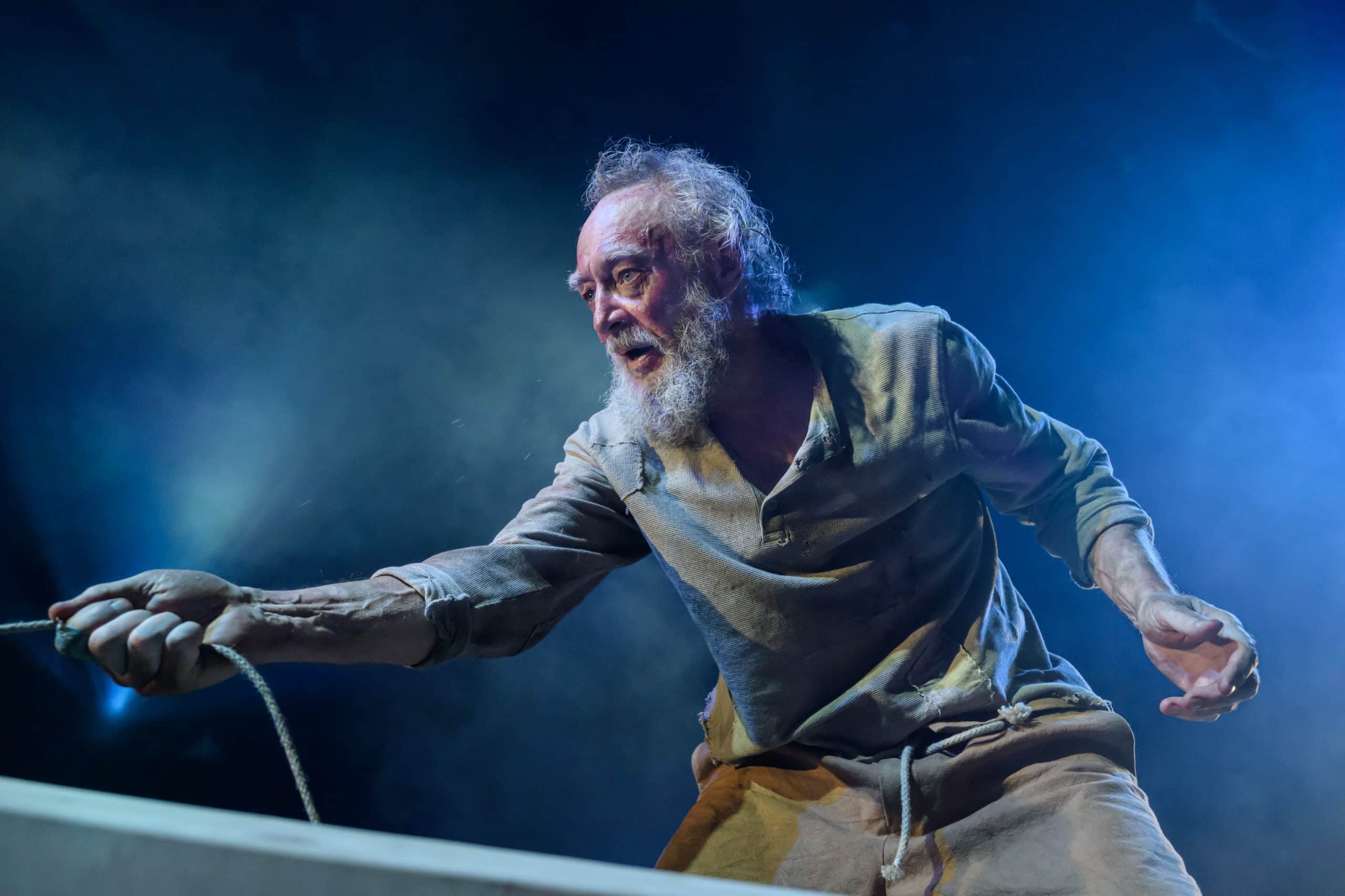 En man drar hårt i en lina, ståendes i en båt.