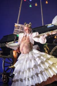 En gravid bisarr figur dansar i vit klänning.