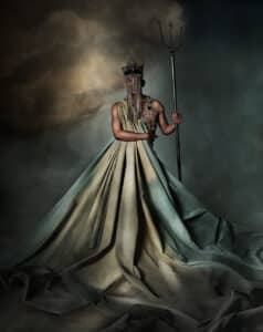 en man står som poseidon med en treudd insvept i ett tygstycke med moln som även fungerar som fond.