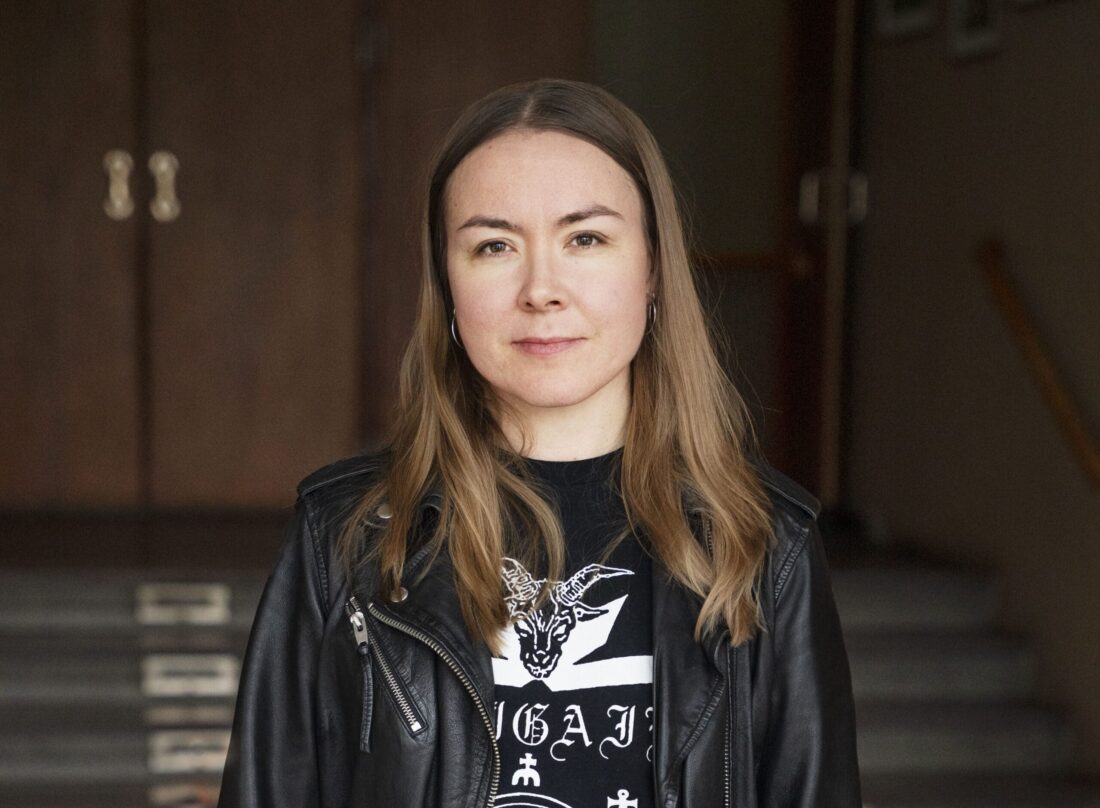 Foto av en kvinna med långt brunt hår iklädd jeans och skinnjacka
