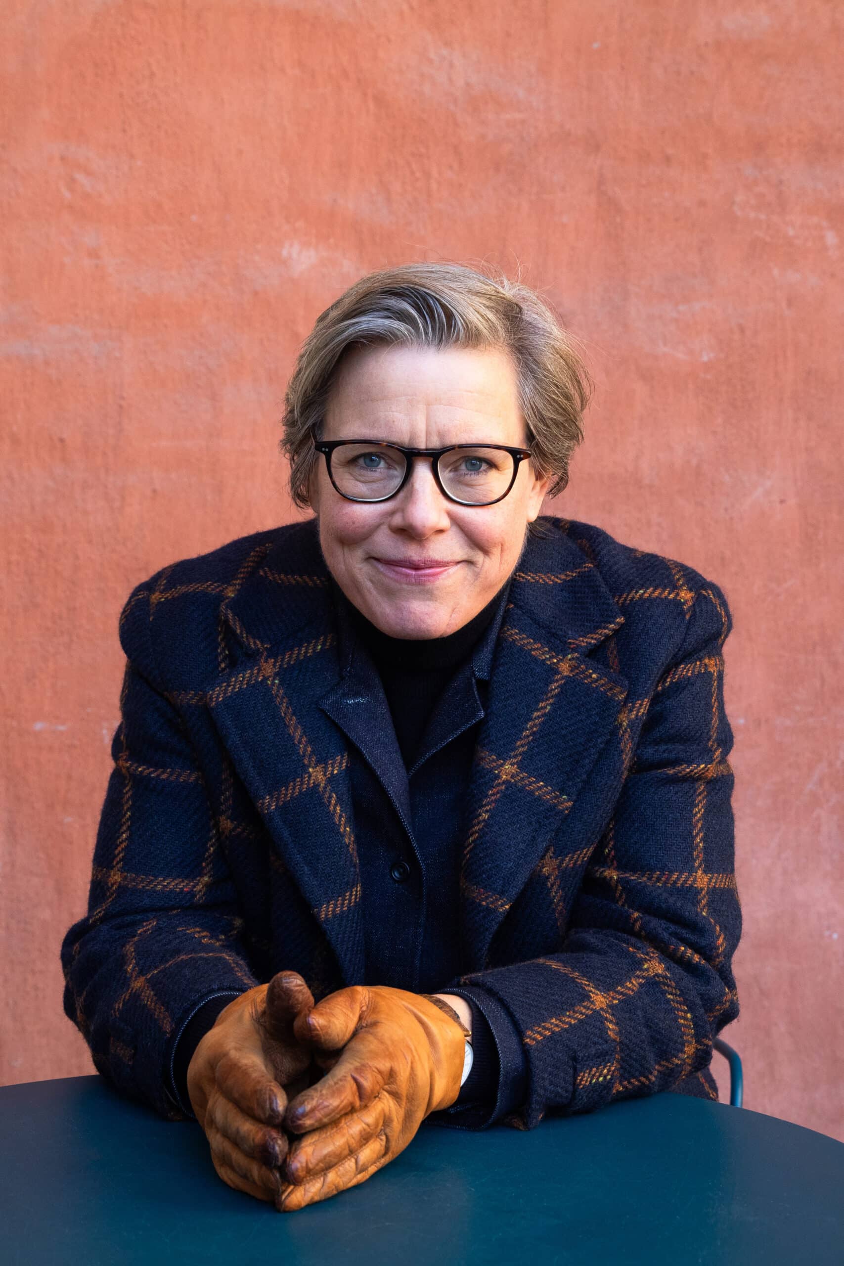 Författaren Lena Andersson i kavaj tittar in kameran och ser glad ut. 